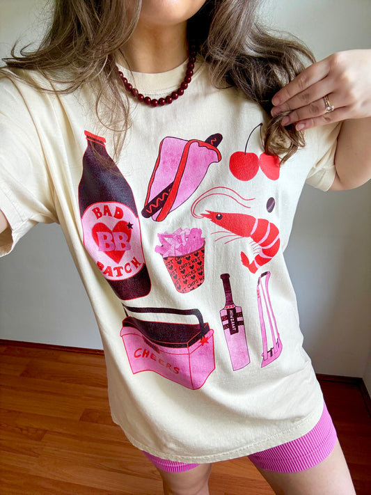 Person wearing an ivory graphic t-shirt with colorful graphics and pink shorts.