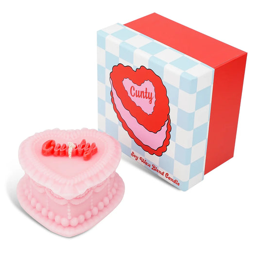 Pink heart-shaped candle with 'Cuntty' text next to its box on a white background