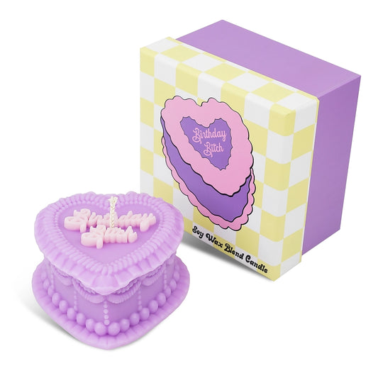 Heart-shaped purple candle with 'Birthday Bitch' text next to its packaging on a white background