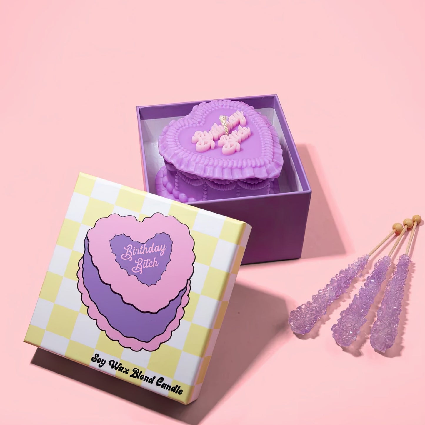 Birthday Bitch heart candle in a checkered box with decorative on a pink background
