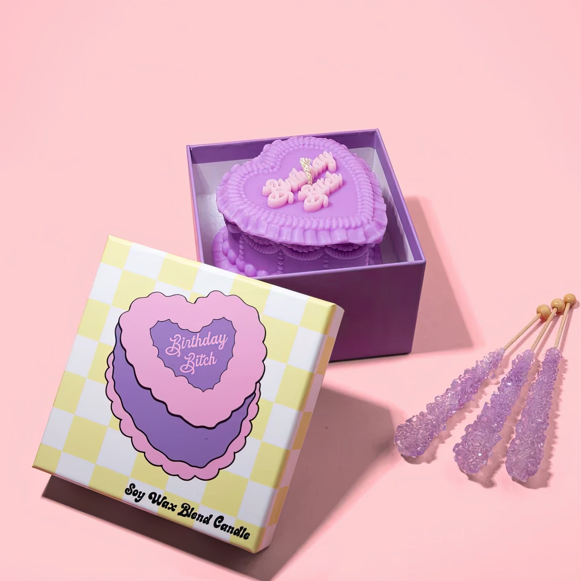 Birthday Bitch heart candle in a checkered box with decorative on a pink background