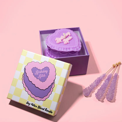 Birthday Bitch heart candle in a checkered box with decorative on a pink background