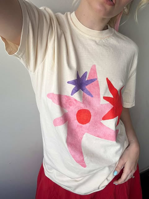Person wearing a white t-shirt with a colorful abstract design against a plain background