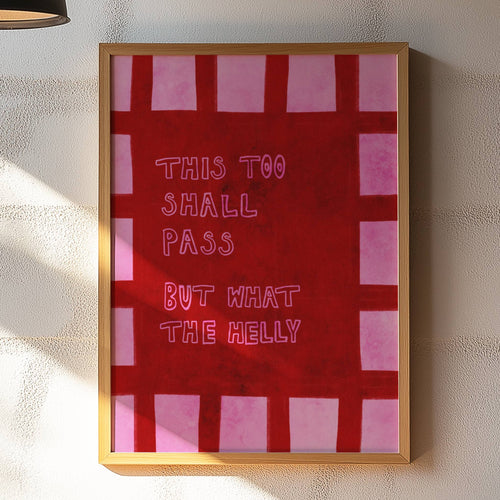 Framed artwork with text on a wall in a room with a lamp and table.